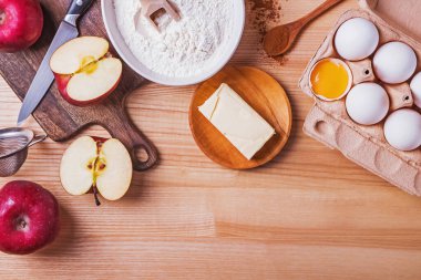 Ahşap masadaki elmalı turta için malzemeler ve araçlar, üst görünüm.