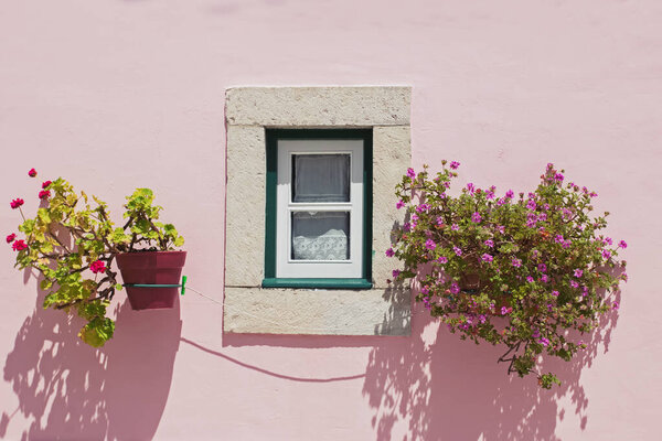 Cute window with flowers on the pink wall facade. — Stock Photo, Image