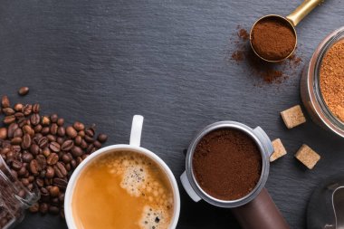En iyi Espresso bardağı, kahve çekirdekleri, toprak ve şeker siyah taş masanın üstünde..
