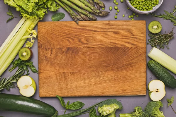 Φρέσκα βιολογικά πράσινα λαχανικά και μπαχαρικά σε γκρίζο πέτρινο τραπέζι. — Φωτογραφία Αρχείου