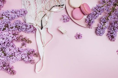 Spring flat lay with lilac flowers, glasses and macarons clipart