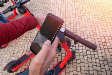 Modern şehrin elektrikli scooter 'ının yanında telefonu tutan adam kilidi açacak..
