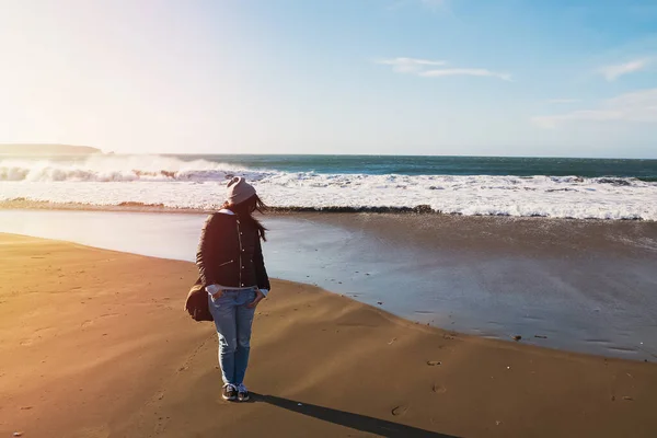 Mulher de chapéu andando na costa do Oceano Pacífico no dia ventoso — Fotografia de Stock