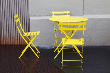 Sarı metal kafe masası ve dışarıda sandalyeler.