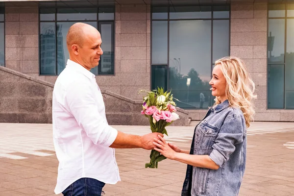 Een man die bloemen geeft aan een vrouw. Lachend koppel op de datum. — Stockfoto