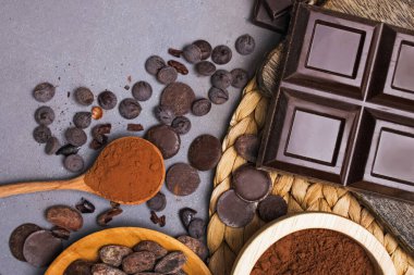 Çikolata ve damla, kakao çekirdeği ve gri arka planda toz.