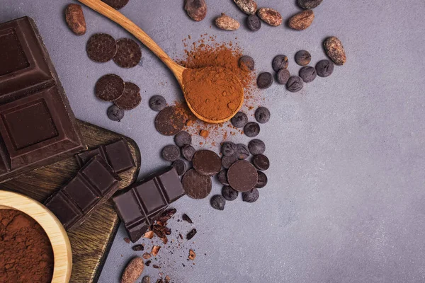 Morceaux et gouttes de chocolat, fèves de cacao et poudre sur fond gris — Photo