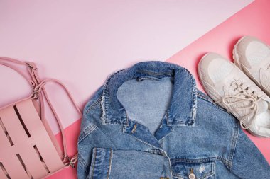 Pembe arka planda kot ceket, çanta ve spor ayakkabılar.