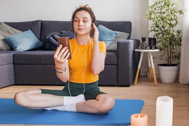 Kadın meditasyon yaparken kulaklıkla müzik dinliyor.