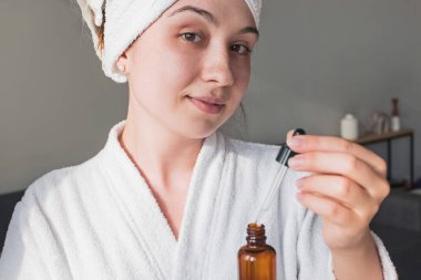 Duştan sonra güzellik serumu süren genç bir kadın.