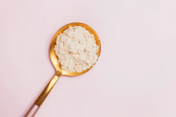 Polvo blanco en una cuchara sobre fondo rosa . —  Fotos de Stock