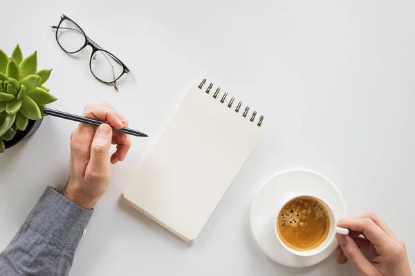 Man writing in the notepad and drinking coffee — Stock Photo, Image