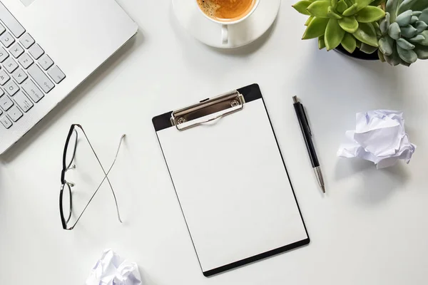 Clipboard with empty paper the table with coffee, glasses, laptop and crumpled paper — Stock Photo, Image