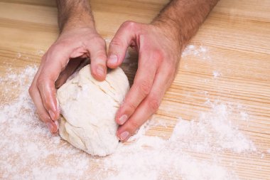 Ahşap masada hamurla çalışan insanlar.