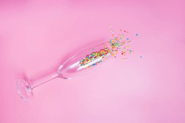 Pembe arka plandaki şampanya bardağında pasta konfetileri var..