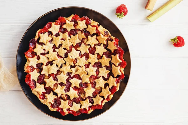 Tarte aux fraises et à la rhubarbe décorée d'étoiles sur table blanche, vue sur le dessus — Photo