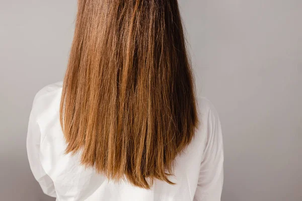 Rückenansicht einer jungen Frau in weißem Hemd mit langem, glänzendem Hör. — Stockfoto