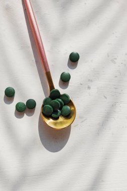 Beyaz masadaki bir kaşığa klorellalı tabletler