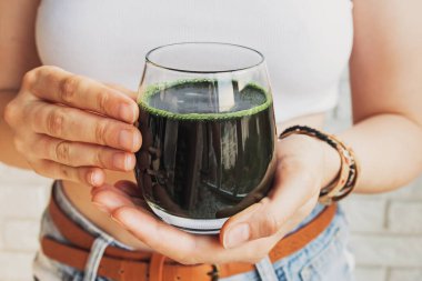 Sağlıklı spirulinalı cam tutan kadın yakından iç.