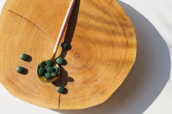 Spirulina o compresse di clorella in un cucchiaio su legno naturale tagliato. — Foto Stock
