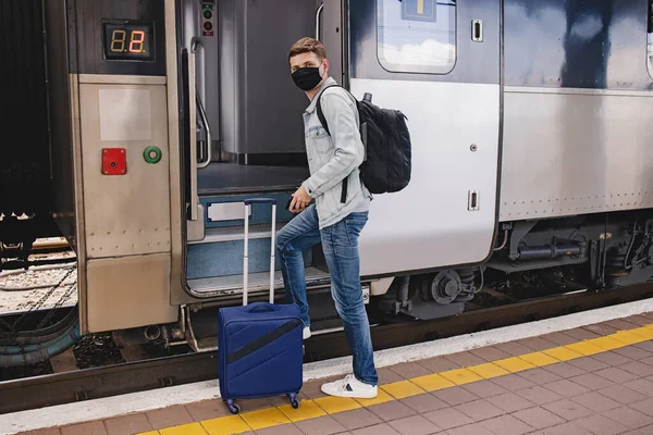 Man wearing protective face maskgoing to enter the intercity train.