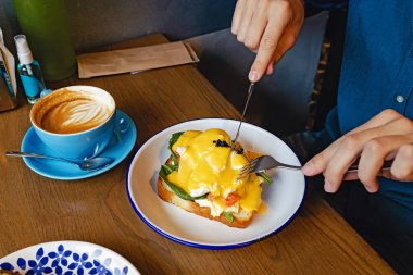 Yumurta yiyen adam Benedict 'i çatal ve bıçakla yakından yiyor..