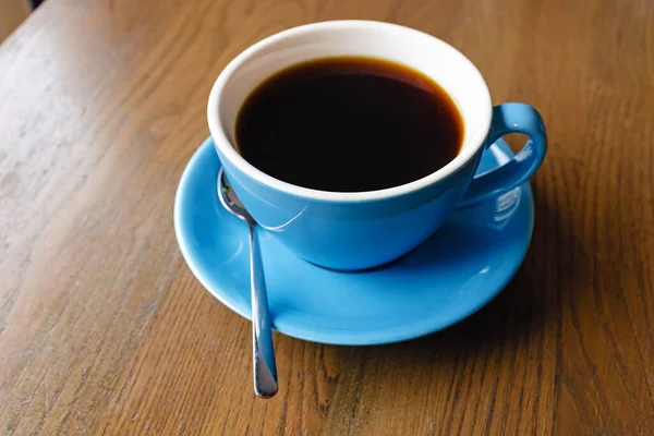 Kék csésze fekete kávé a fa asztalon — Stock Fotó