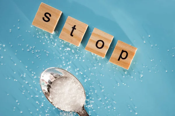 Word STOP aus Holzbuchstaben und raffiniertem Zucker auf blauem Hintergrund. — Stockfoto