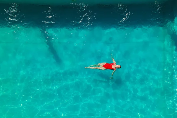 Woman in red bikini are swimming in the pool with turquoise water