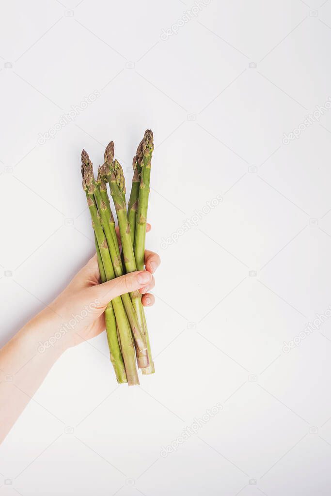 Female hand holds fresh green asparagus.