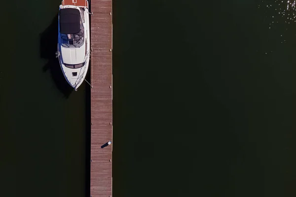 Photo aérienne de petit bateau à moteur ou yacht debout près de la jetée en bois — Photo