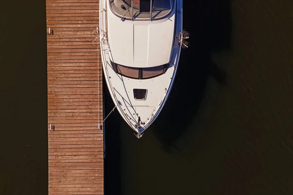 Aerial view photo of small motor boat or yacht standing near the wooden pier — Stock Photo, Image