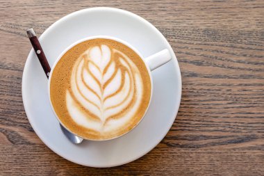 Kapuçino kahve sosu ve ahşap masa üzerinde bırakılmış latte sanatı,