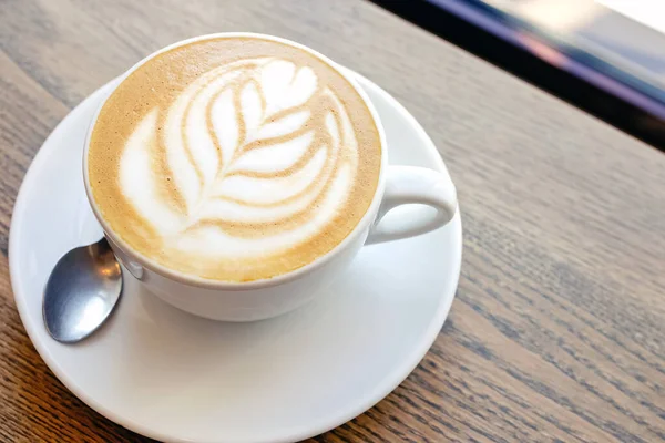 Крупный план горячего кофе капучино с листовой формой латте — стоковое фото