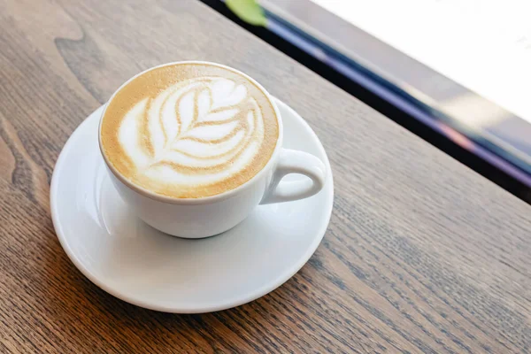 Капучино кофе оставить форму латте искусства на деревянный стол — стоковое фото