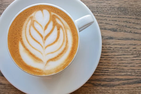 Kapuçino kahve sosu ve ahşap masa üzerinde bırakılmış latte sanatı,