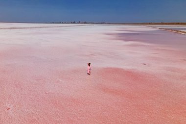Parlak pembe salin yüzeyinde yürüyen bir kadın.