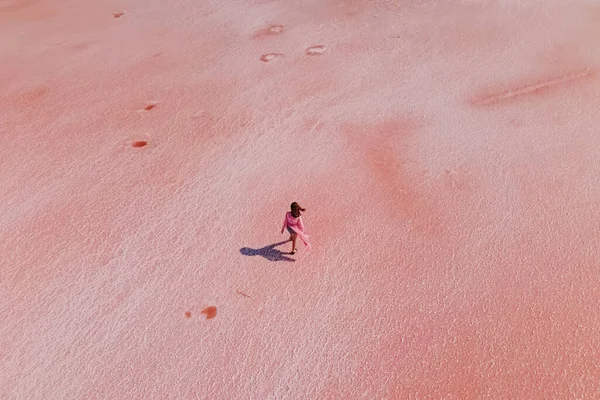 Mulher andando sobre a superfície da solução salina de cor rosa brilhante — Fotografia de Stock