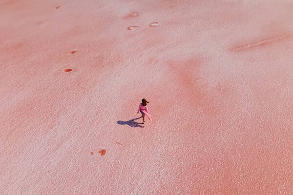 Woman walking on the surface of saline of bright pink color — Stock Photo, Image