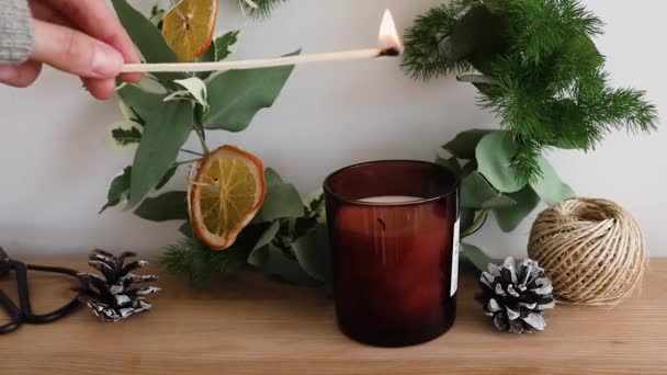 La mano de las mujeres enciende una vela en una mesa con decoración de Navidad — Vídeos de Stock