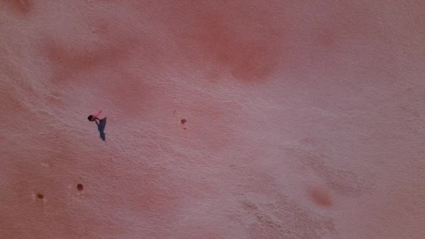 Letecký pohled na ženu v růžovém plášti kráčející po růžovém fyziologickém roztoku — Stock video