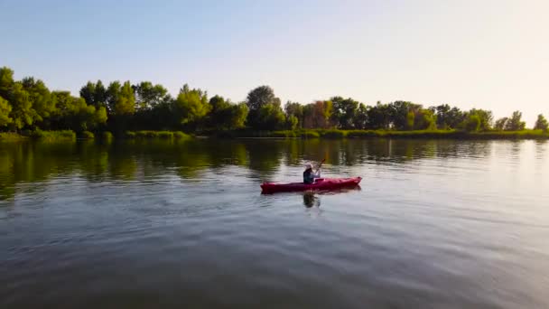 Young female traveller floats in kayak on river at warm ening sunlight — Stock Video