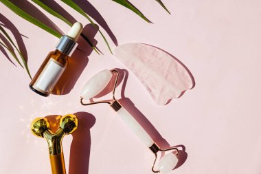 Yüz masajı ve yüz bakımı serumu için farklı aletler. Dümdüz, sert gölgeli güneş ışığında yatıyordu..