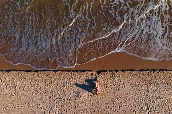 Vista aérea de la mujer sentada en la playa de arena. — Foto de Stock