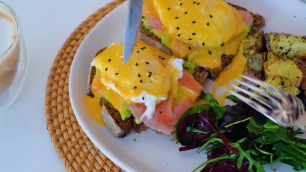 Gepocheerd ei snijden op geroosterd brood met avocado en zalm — Stockvideo