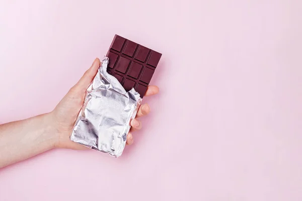 Main tient la barre de chocolat noir dans une feuille. — Photo