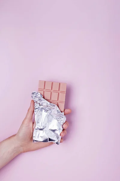 Kobieca dłoń trzyma tabliczkę malinowej czekolady o smaku — Zdjęcie stockowe