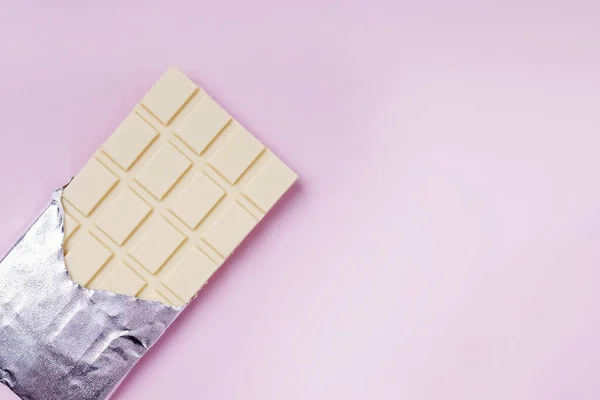 Biała czekolada w folii na różowym tle — Zdjęcie stockowe