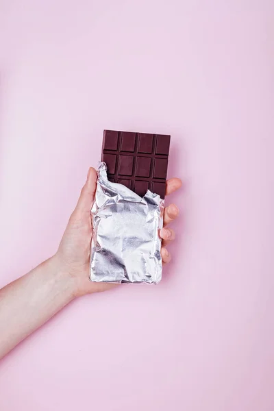 Mano tiene la barra di cioccolato fondente in lamina. — Foto Stock