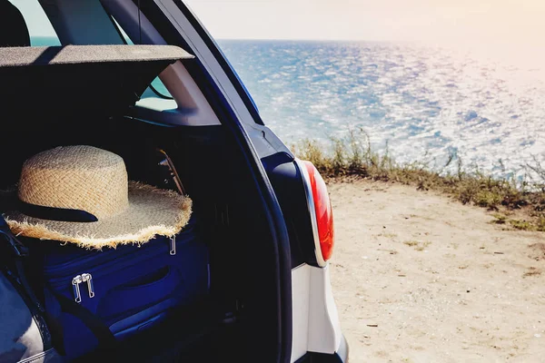 Close-up of the trunk of a car with suitcase and straw hat in it — Stock Photo, Image